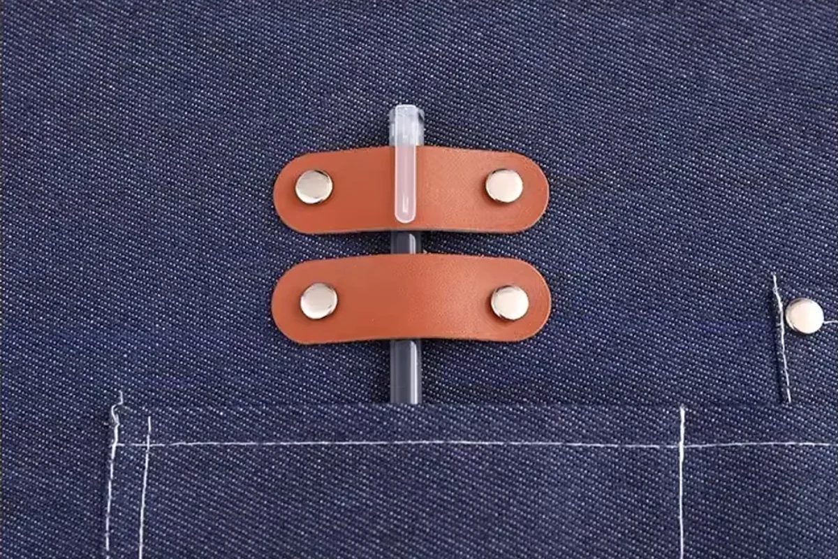 Metal rivets securing brown tabs to a dark apron.