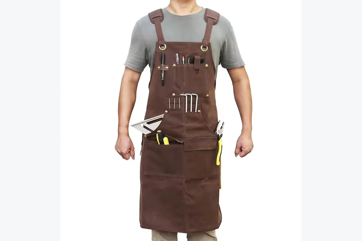 Brown work apron with multiple pockets and loops holding hand tools.
