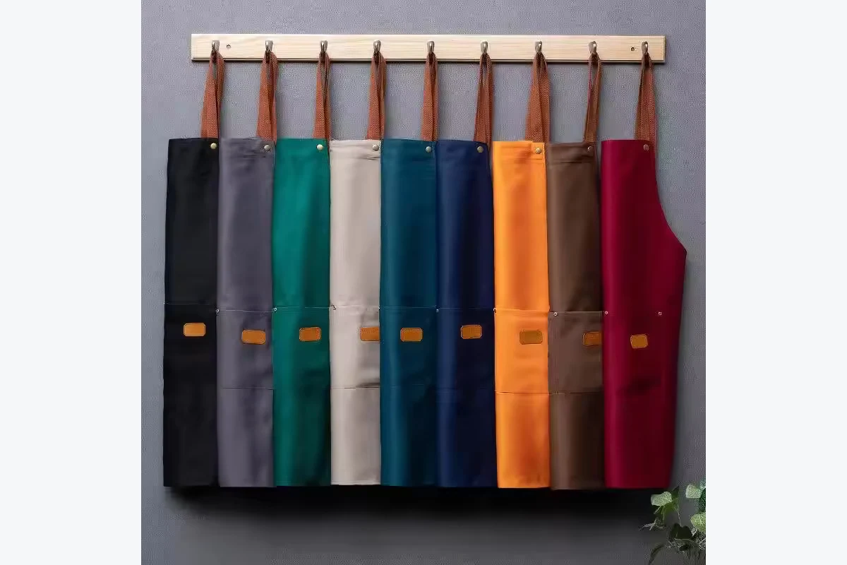 Bib aprons in several colors hanging from a wooden rack.