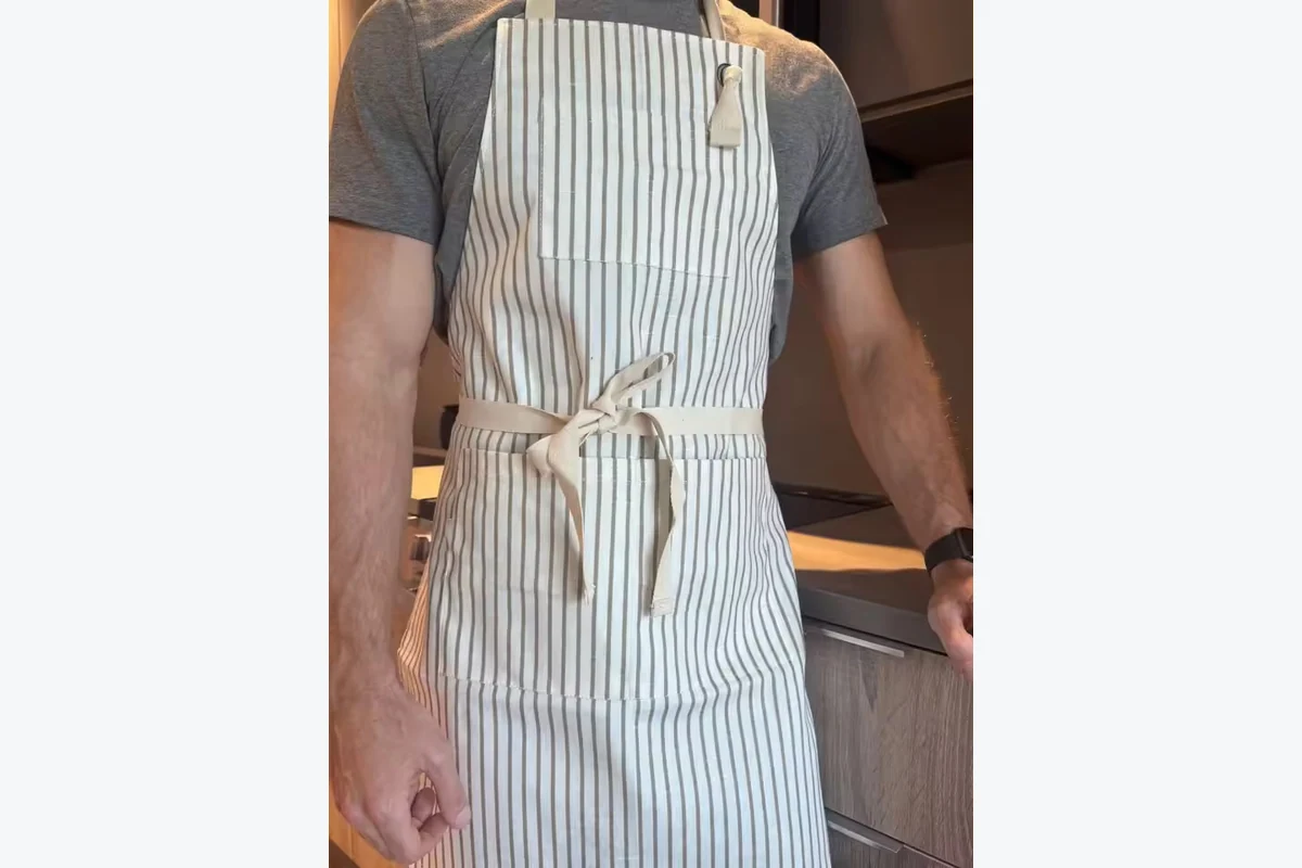 Light-colored apron with narrow vertical stripes and a front waist tie.