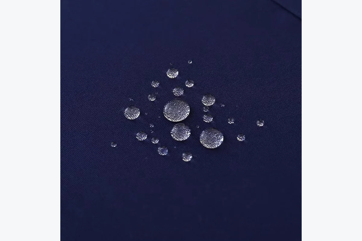 Water droplets resting on dark blue fabric.