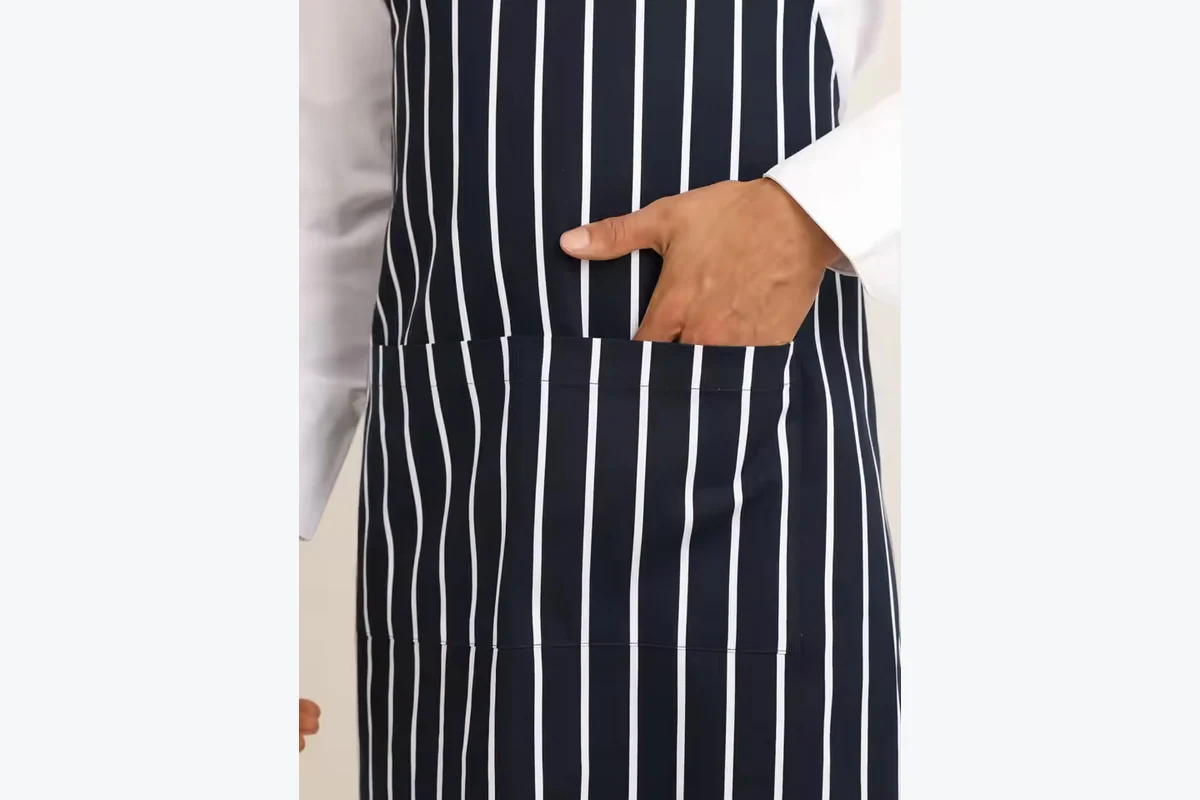 A hand resting in a front apron pocket.