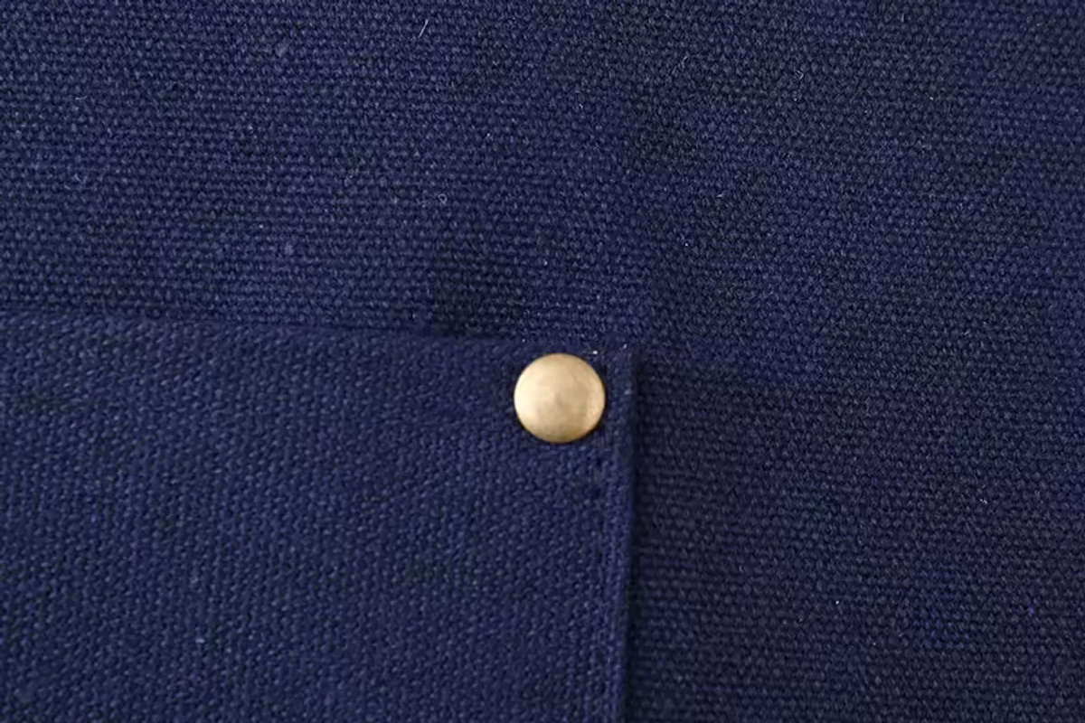 A front apron pocket with a metal rivet and visible stitching.