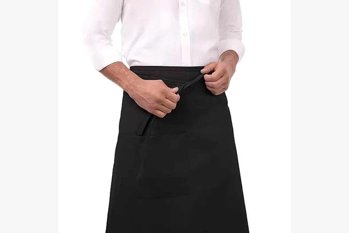 A black waist apron being tied at the front.