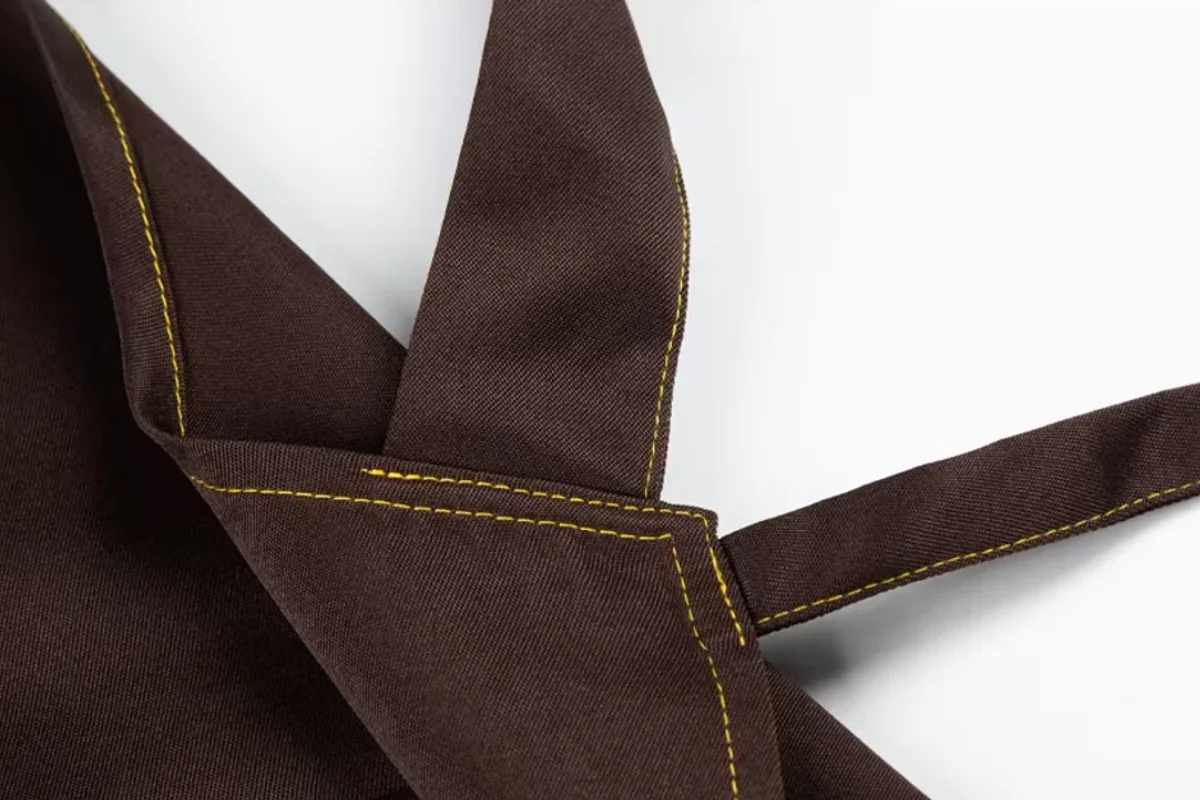 Brown apron straps and edges with yellow stitching.