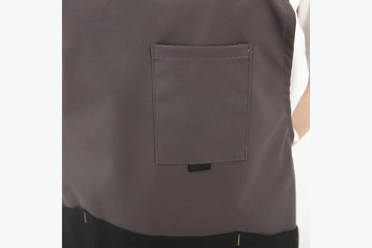 A rectangular chest pocket on a gray and black apron.