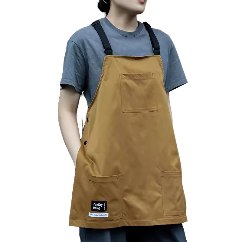Tan apron with black shoulder straps and front pockets.