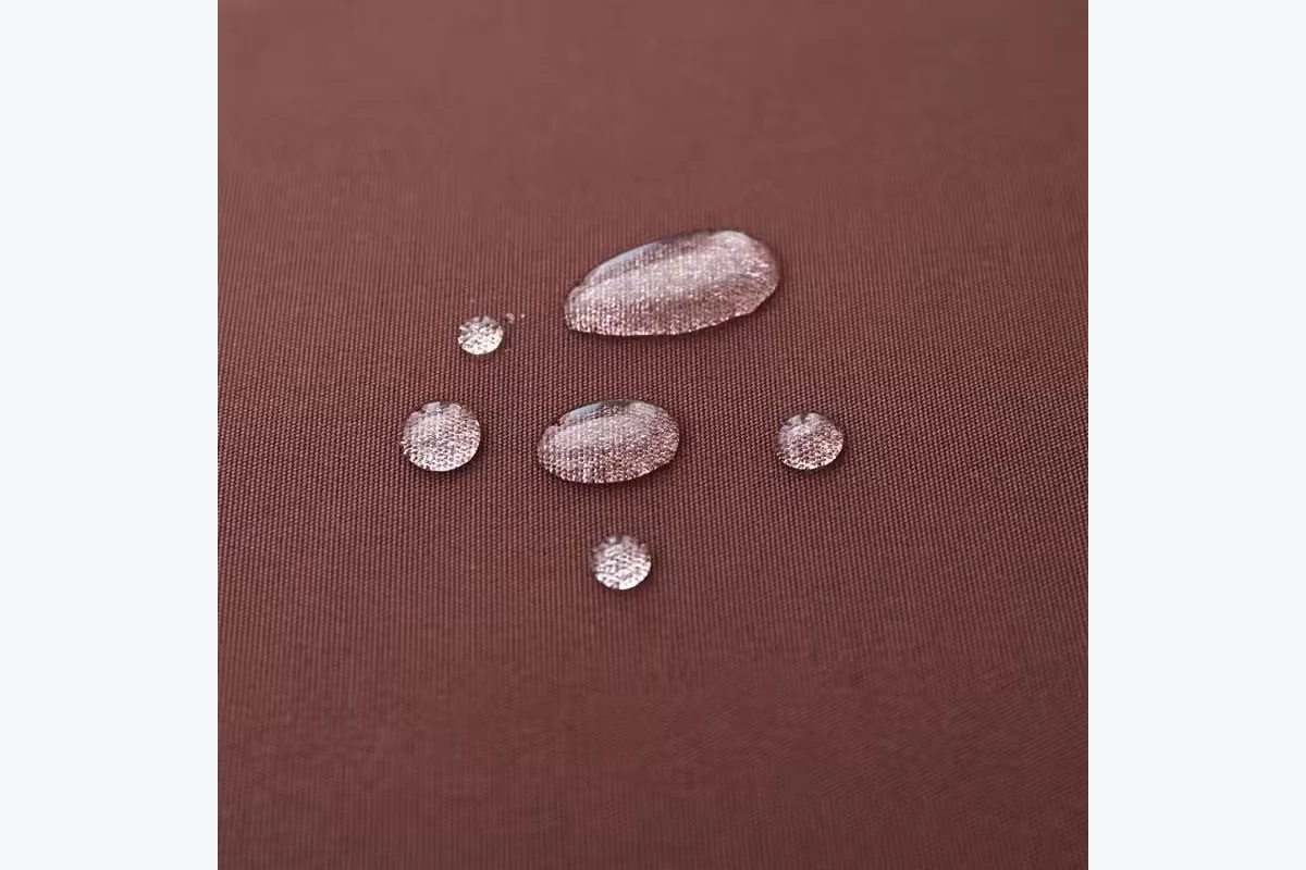 Water droplets resting on a brown fabric surface.