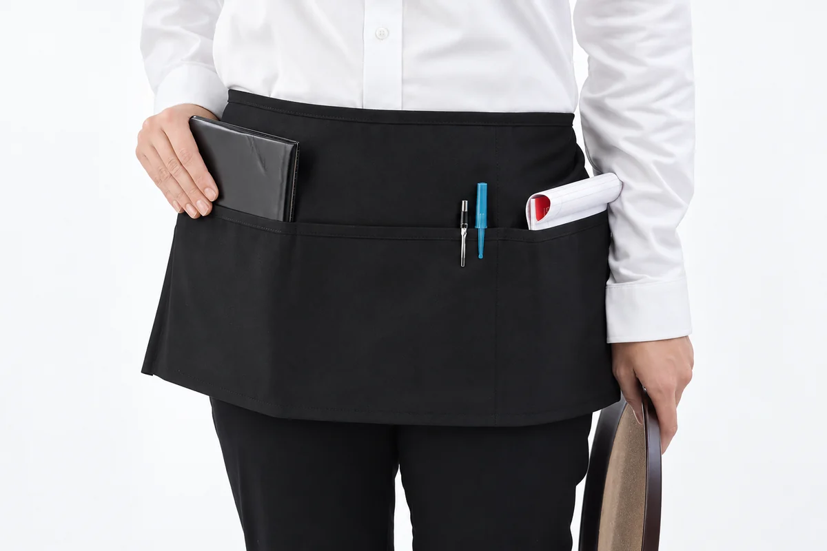 Black waist apron with divided front pockets.